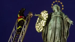 Firefighter putting wreath of flowers on Mary 