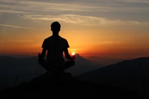 Man meditating on a beautiful mountain sunset. Photo by Indian Yogi (Yogi Madhav) on Unsplash.